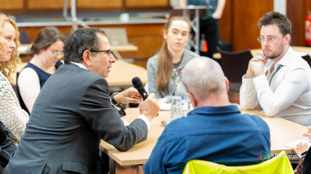 UKDS Poverty in Data impact event 2024 - Professor Donald Hirsch sits, discussing with early career researchers